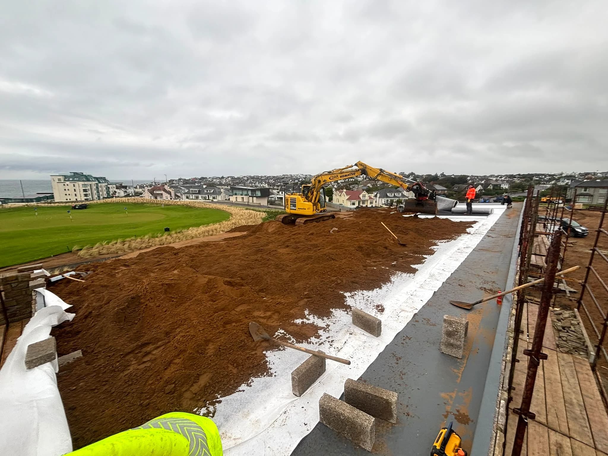 Portstewart Golf Club - excavator spreading soil onto the green roof with the links and north coast beyond